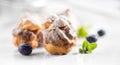 Profiterole or cream puff with filling, powdered sugar topping with berries, on white background
