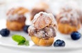 Profiterole or cream puff with filling, powdered sugar topping with berries, on white background