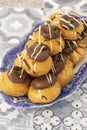 Profiteroles, coated in chocolate, stacked on a pattermed blue and white plate. Royalty Free Stock Photo