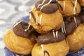 Profiteroles, coated in chocolate, stacked on a pattermed blue and white plate. Royalty Free Stock Photo