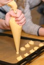 Profiteroli cooking process with dough balls, hands with special culinary tube