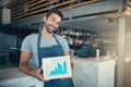 Profiting from his passion. Portrait of a young man holding a digital tablet with a graph on the screen at a coffee shop