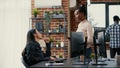 Programer standing up holding digital tablet talking with coder sitting at desk in front of computer screen Royalty Free Stock Photo