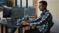 Programer thinking while touching beard and fixing glasses while typing on laptop sitting at desk Royalty Free Stock Photo