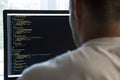 Programmer from behind and programming code on computer monitor Royalty Free Stock Photo