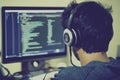 A programmer engages deeply in coding, wearing headphones and concentrating on the multiple lines of code displayed on Royalty Free Stock Photo