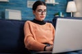 Programmer with glasses holding laptop on sofa writting code. Royalty Free Stock Photo