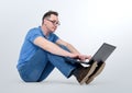 Programmer in glasses working on a laptop and sitting on the floor