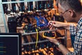 Programmer holding a wattmeter measuring cryptocurrency mining rig