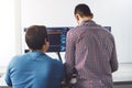 Back view of two young IT guys in front of computer screens, writing a new code Royalty Free Stock Photo