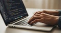 Close-up of programmer coding on a laptop with colorful code on screen Royalty Free Stock Photo