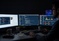 Programmer working late at night on multiple monitors displaying code and data {Ai generated Royalty Free Stock Photo