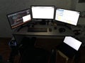 Programmer workspace with multiple monitors and laptop in dark room Royalty Free Stock Photo