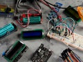 Programmers and Arduino with peripherals and expansion boards lie on a gray background. Do-It-Yourself