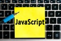 programming language inscription `JavaScript` on a yellow sheet of sticker paper on the background of a computer keyboard