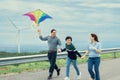 Progressive happy carefree family vacation concept flying kite with wind turbine Royalty Free Stock Photo