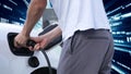 Progressive man charge electric car with technology background of binary code. Royalty Free Stock Photo