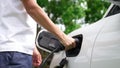 Progressive man install cable plug to his EV car from home charging station. Royalty Free Stock Photo