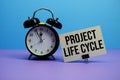 Project Life Cycle text with alarm clock on blue and purple background Royalty Free Stock Photo