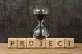 Project timeline countdown, launch business or start up company, hourglass or sandglass on wooden cube block with alphabet