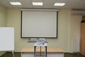 Projection screen in the boardroom with projector on table Royalty Free Stock Photo
