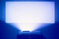 projector in action with illuminated warm blue screen