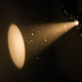 A projector emits a cone of light in a dim environment, illuminating swirling dust Royalty Free Stock Photo