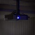 Projector hanging on ceiling of meeting room with all lights out