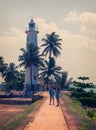 The promenade and the lighthouse, green palm trees and tourists