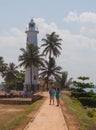 The promenade and the lighthouse, green palm trees and tourists