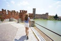 Promenade riverside in Verona, Italy. Beautiful lady walking along promenade with medieval fortress Castelvecchio castle and Royalty Free Stock Photo