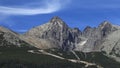 Prominent mountain with observatory on the top and wind blown clouds. Cable car building and ski slopes in the foreground, High Royalty Free Stock Photo