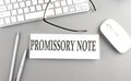 PROMISSORY NOTE text on paper with keyboard on grey background