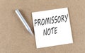 PROMISSORY NOTE text on sticky note on a cork board with pencil