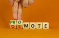 Promote or demote symbol. Businessman turns cubes and changes the word `demote` to `promote`. Beautiful orange background. Royalty Free Stock Photo