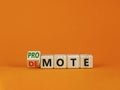 Promote or demote symbol. Turned a cube and changed the word `demote` to `promote`. Beautiful orange table, orange background. Royalty Free Stock Photo