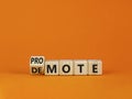 Promote or demote symbol. Turned a cube and changed the word `demote` to `promote`. Beautiful orange table, orange background. Royalty Free Stock Photo