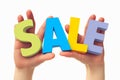 Promotional concept hands holding colorful letters spelling Sale