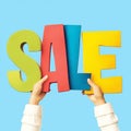 Promotional concept hands holding colorful letters spelling Sale