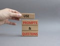 Prompts and Questions symbol. Concept word. Use Prompts and Questions on wooden blocks. Beautiful grey background. Businessman Royalty Free Stock Photo