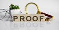 PROOF concept on wooden cubes and flower ,glasses ,coins and magnifier on the white background Royalty Free Stock Photo