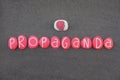 Propaganda word composed with red colored stone letters and a boxing glove design over black volcanic sand Royalty Free Stock Photo
