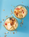 Proper nutrition, breakfast. Welness - granola with yogurt and fruits: banana and apple, in glass cups on a blue background. Top