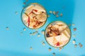 Proper nutrition, breakfast. Welness - granola with yogurt and fruits: banana and apple, in glass cups on a blue background, top
