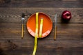 Proper nutrition for lose weight. Empty plate, apple and measuring tape on dark wooden background top view