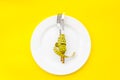 Slim concept with plate, flatware and measuring tape on yellow background top view