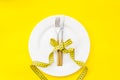 Slim concept with plate, flatware and measuring tape on yellow background top view