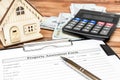Property assessment form with money, calculator and model of house on the table. Property valuation concept
