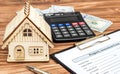 Property assessment form with money, calculator and model of house on the table. Property valuation concept