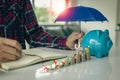 Property insurance guidelines with an umbrella on a piggy bank and a pile of coins on a table